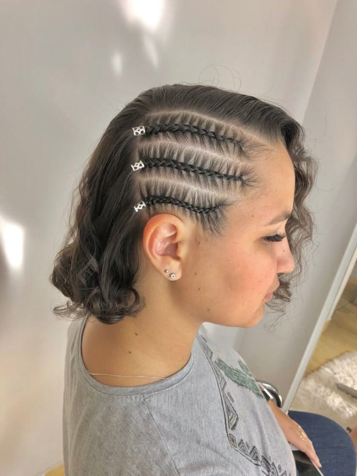 Three fine accent braids with silver cuffs woven into short natural curls.