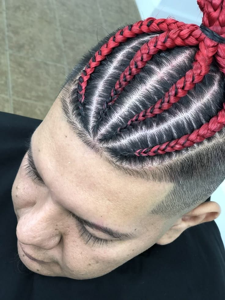 Men's braided bun in deep red with a sharp fade and scalp pattern.